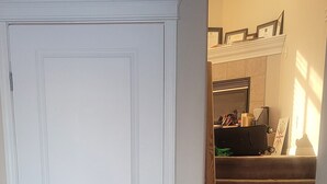 Un pasillo con una puerta blanca, escaleras alfombradas y suelo de baldosas.