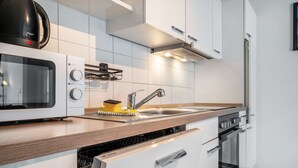 A modern kitchen with a microwave, stove, sink, and dishwasher. - Holiday Apartment with View of Jever Castle (Jever)