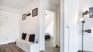 A modern interior with a white bench, a floor lamp, and a staircase leading to another room. - Holiday Apartment with View of Jever Castle (Jever)