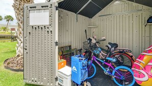 A covered bike storage area with a large metal container, a bicycle, and a colorful inflatable object. - Private Pool w/ Canal Views: Apollo Beach Getaway (Apollo Beach)