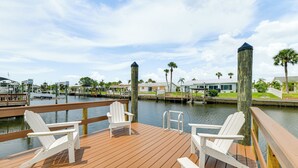 A wooden deck with white Adirondack chairs overlooking a marina with boats and a calm water body. - Private Pool w/ Canal Views: Apollo Beach Getaway (Apollo Beach)
