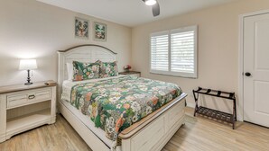 A bedroom with a bed, nightstand, lamp, ceiling fan, window with blinds, and a door. - Private Pool w/ Canal Views: Apollo Beach Getaway (Apollo Beach)