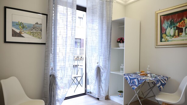Une pièce comprenant une table à manger, deux chaises, une étagère avec une plante en pot et un tableau encadré accroché au mur.