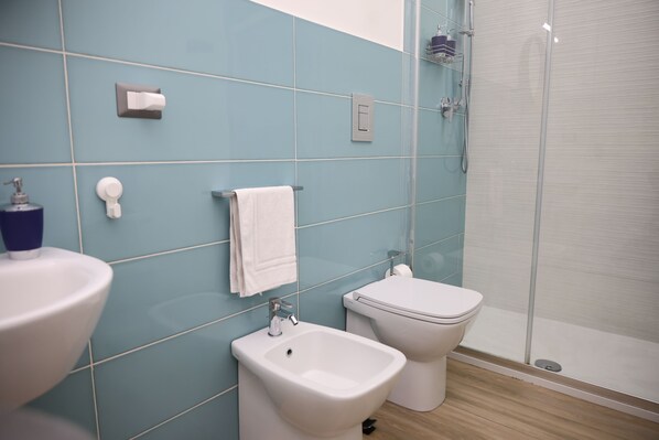 Un baño con bidé, inodoro y lavamanos.