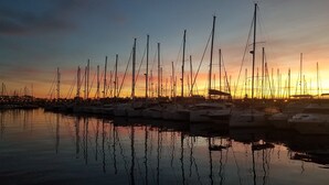 Un port de plaisance où de nombreux bateaux sont amarrés au coucher du soleil.