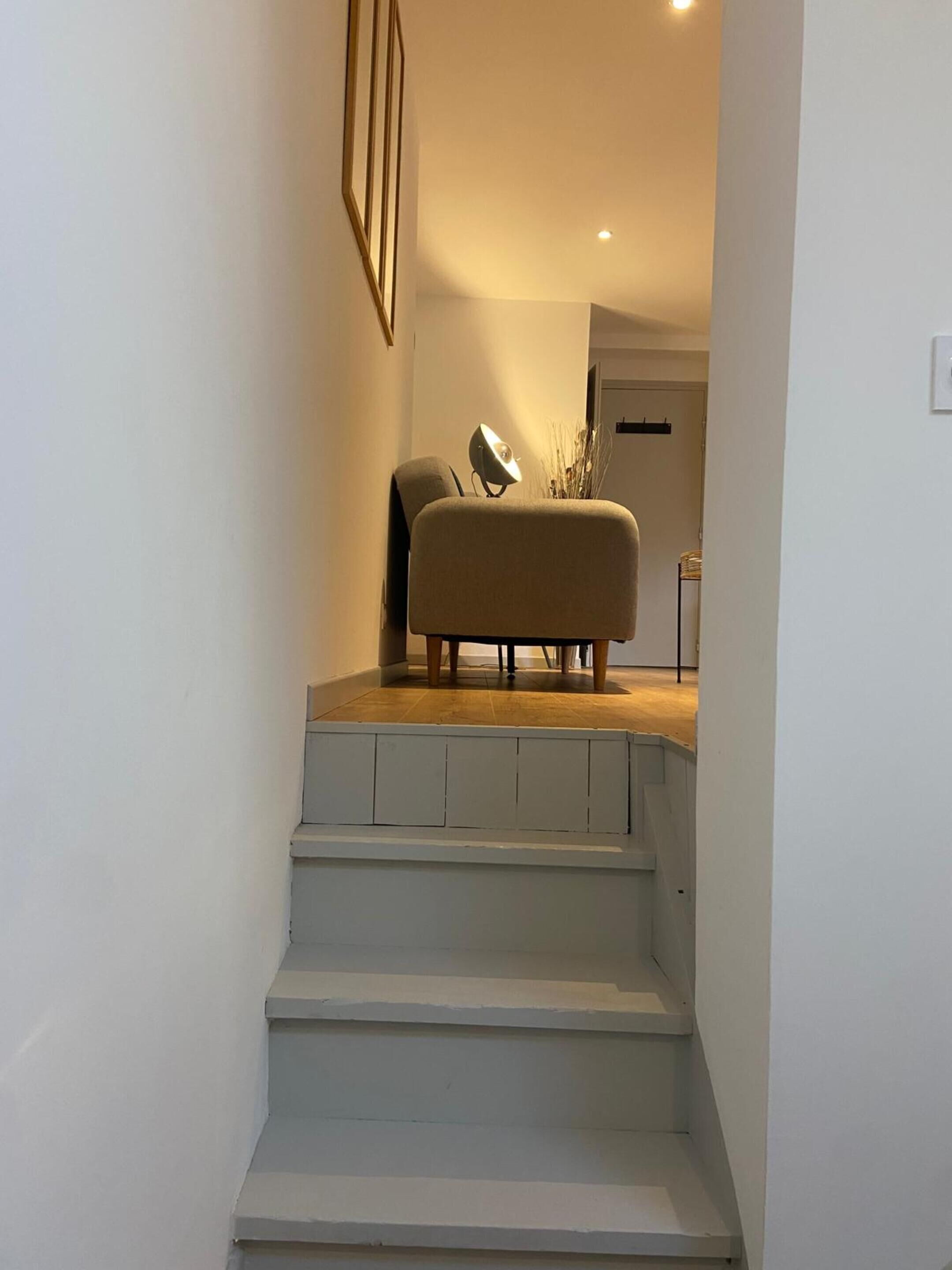 En trappa som leder upp till ett vardagsrum med en soffa och en lampa.