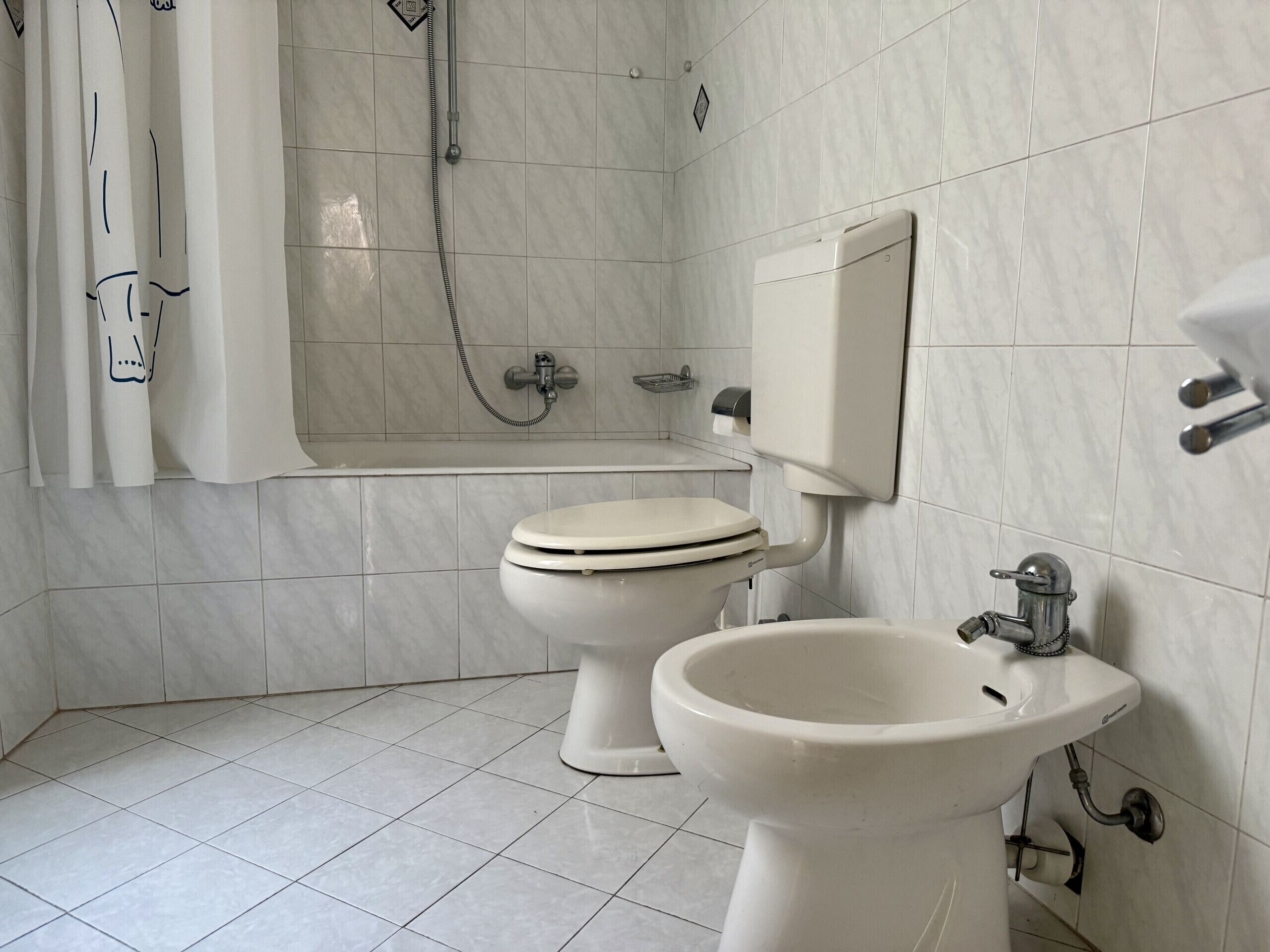 A bathroom with a toilet, bidet, and bathtub.