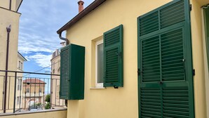 A building with green shutters, a tiled balcony, and a clear sky. - La Casa de Rina (Imperia)