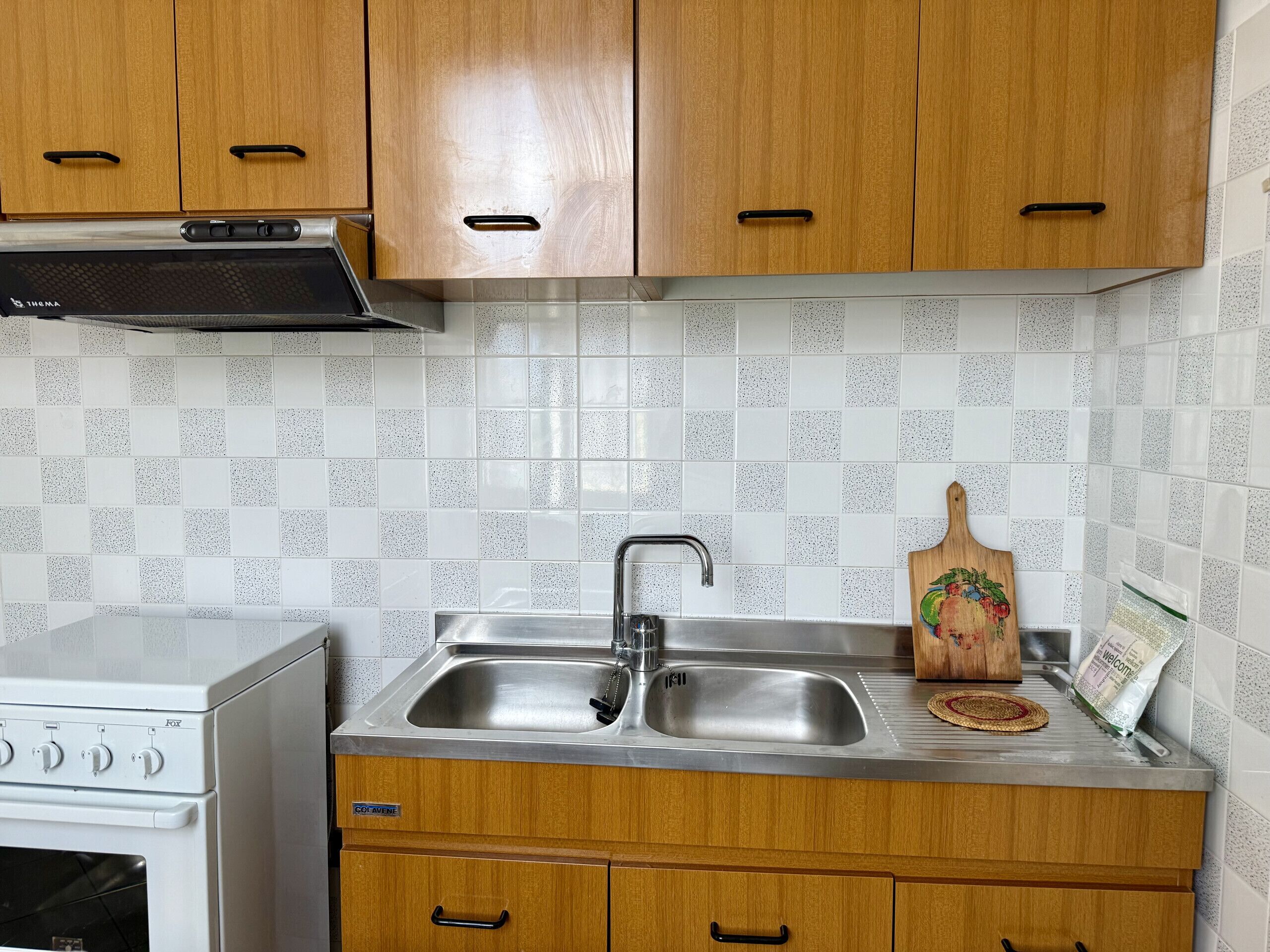 A kitchen with wooden cabinets, a stainless steel sink, and a white stove.