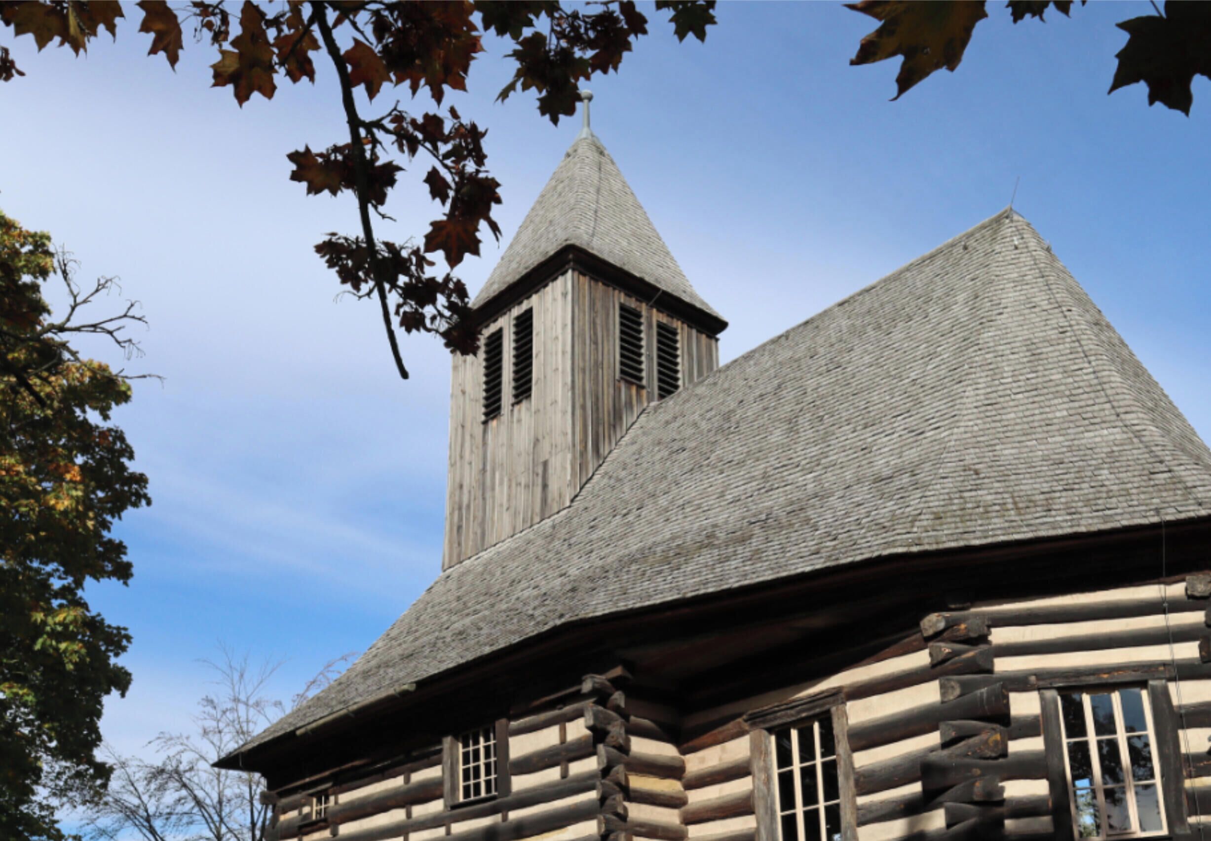 A log cabin with a steeply pitched roof and a prominent tower.