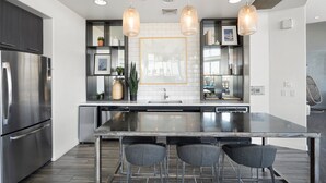 A modern kitchen with a large island, stainless steel appliances, pendant lighting, and a view into the dining area. - Luxury Tempe Stay 1BR w/ Patio, Gym & Business Center (Tempe)