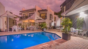 A swimming pool with white outdoor furniture and a covered seating area. - Khayalami Hotel Mbombela (Mbombela)
