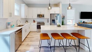 A modern kitchen with white cabinets, stainless steel appliances, and a central island with bar stools.