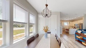 A spacious dining area with a long table, benches, and a chandelier.