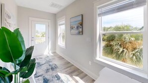 A spacious hallway with a large window offering a view of palm trees and a clear sky.