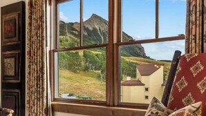 Ein Zimmer mit großem Fenster und Blick auf einen Berg und ein Gebäude.