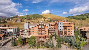 Ein Hotel mit mehreren Gebäuden, einem Skihang im Hintergrund und einer Berglandschaft.