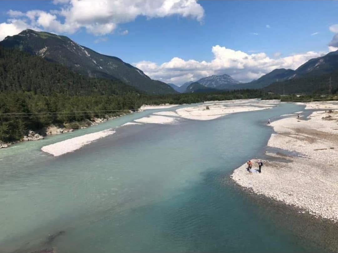 Une rivière aux rives sablonneuses, et une personne se tenant sur la rive droite.