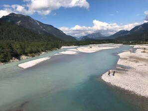 Ein Fluss mit sandigem Ufer und eine Person, die am rechten Ufer steht.