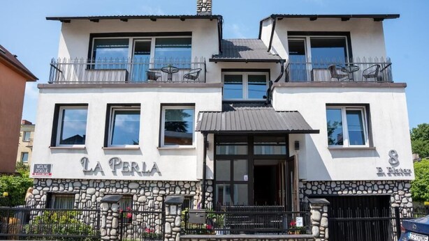 A two-story building with a stone facade, balconies, and a sign reading "LA PERLA." - La Perla (Międzyzdroje)