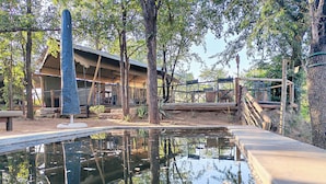 A tranquil outdoor area with a small pond, wooden structures, and a covered seating area. - TIMELESS THRILLS: EMBRACE THE ESSENCE OF A CONSERVATION-DRIVEN EXPERIENCE (Phalaborwa)