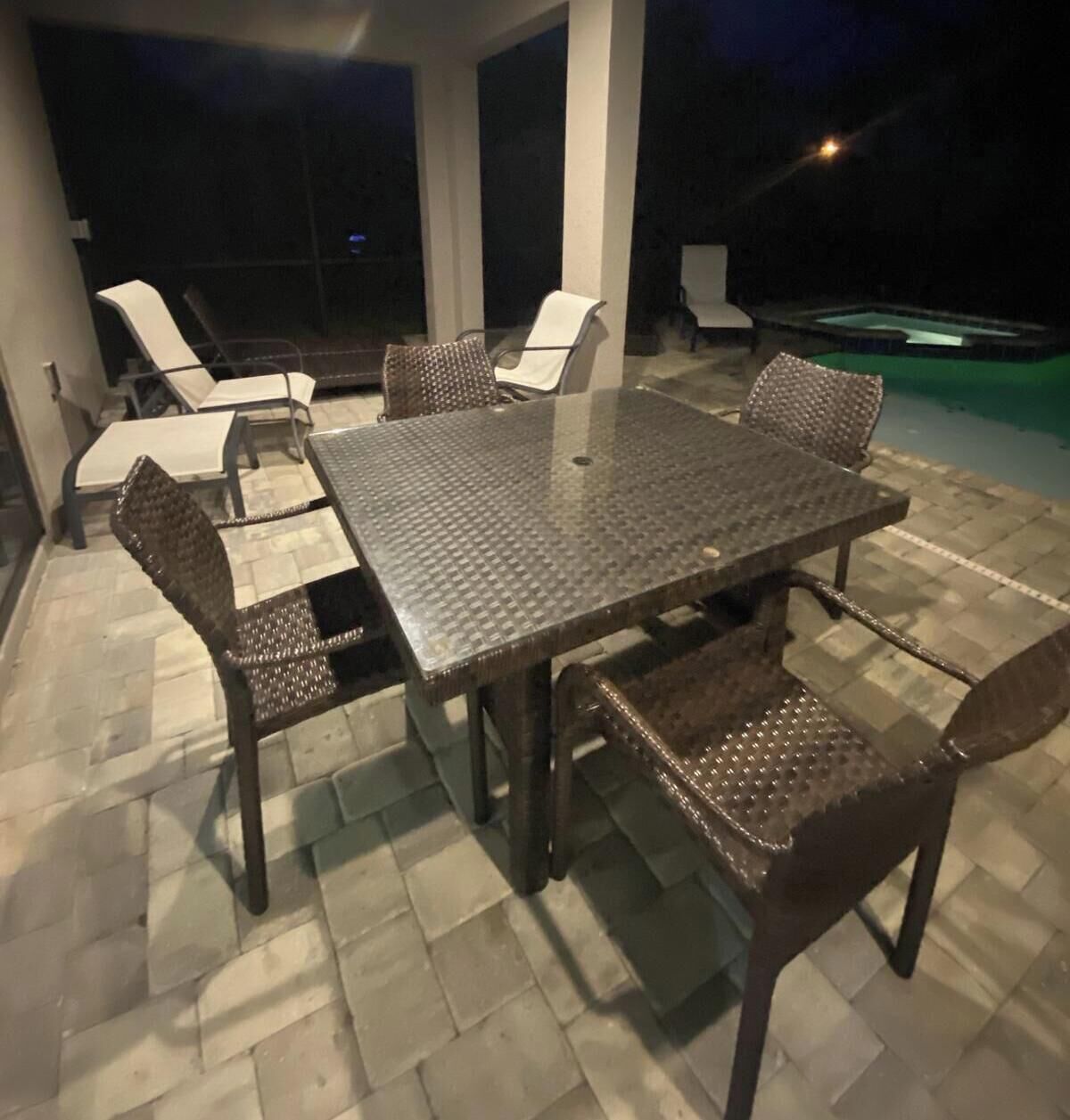 Une terrasse extérieure avec une table rectangulaire et six chaises, entourée de carreaux de pierre.