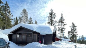 A cabin with a snow-covered roof, surrounded by snow, with a car parked in front. - Magical west view in Sälen, 8 beds in 3 bedrooms in cozy spacious log cabin (Dalarnas län)