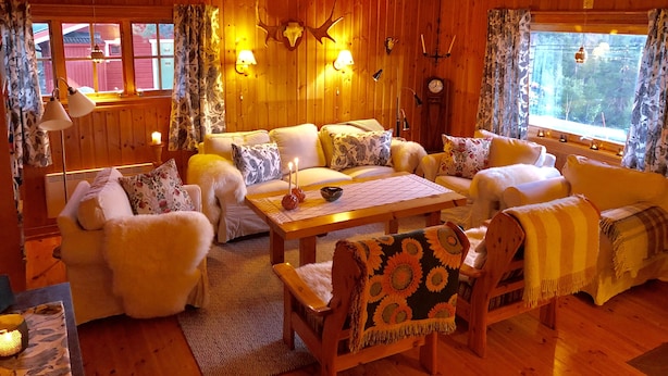 A cozy cabin interior with wooden walls, a sofa set, a dining table, and a fireplace. - Magical west view in Sälen, 8 beds in 3 bedrooms in cozy spacious log cabin (Dalarnas län)