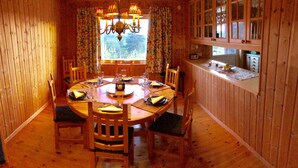 A wooden dining room with a round table set for six, surrounded by chairs. - Magical west view in Sälen, 8 beds in 3 bedrooms in cozy spacious log cabin (Dalarnas län)