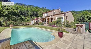 Una casa circondata da un giardino e alberi, con una piscina.