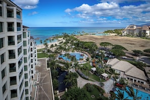 A resort with a pool, palm trees, and a view of the ocean.