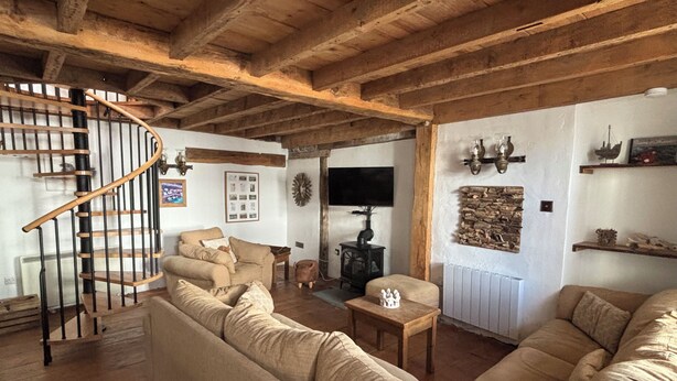 A cozy living room with a wooden staircase, a sofa set, a small table, and a television. - Fantastic 1-bedroom house in Portpatrick (Portpatrick)