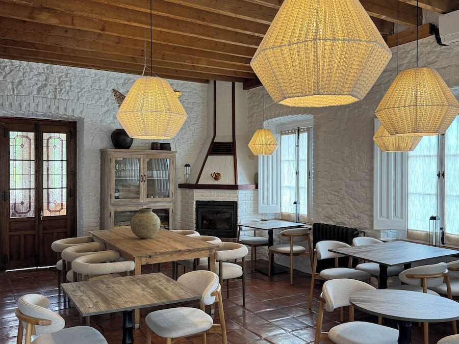 Un ambiente acogedor con mesas y sillas de madera, una chimenea e innovadoras lámparas de fibra hexagonal.