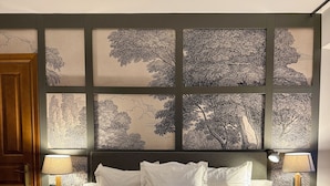 A hotel room with a large bed, two nightstands, a wooden door, and a wall with black and white tree prints. - Hotel Quinta Solera (Oviedo)