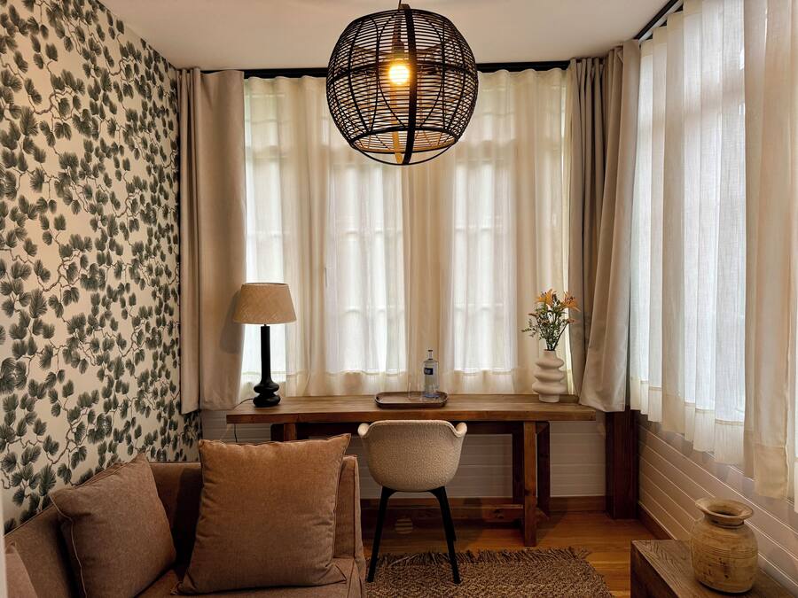 Una sala de estar acogedora con un sofá, una silla, una mesa de madera y una lámpara decorativa.
