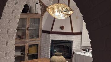 Un comedor con una mesa de madera, sillas, una lámpara colgante y una pared de ladrillo.