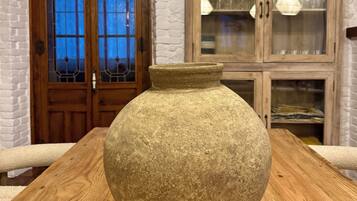 A stone vase on a wooden table in a room with a stone wall and wooden door.