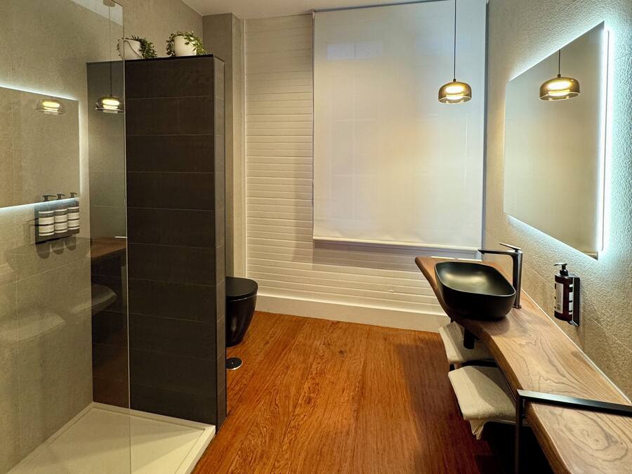 A modern bathroom with a glass shower enclosure, a wooden vanity, and a large mirror.