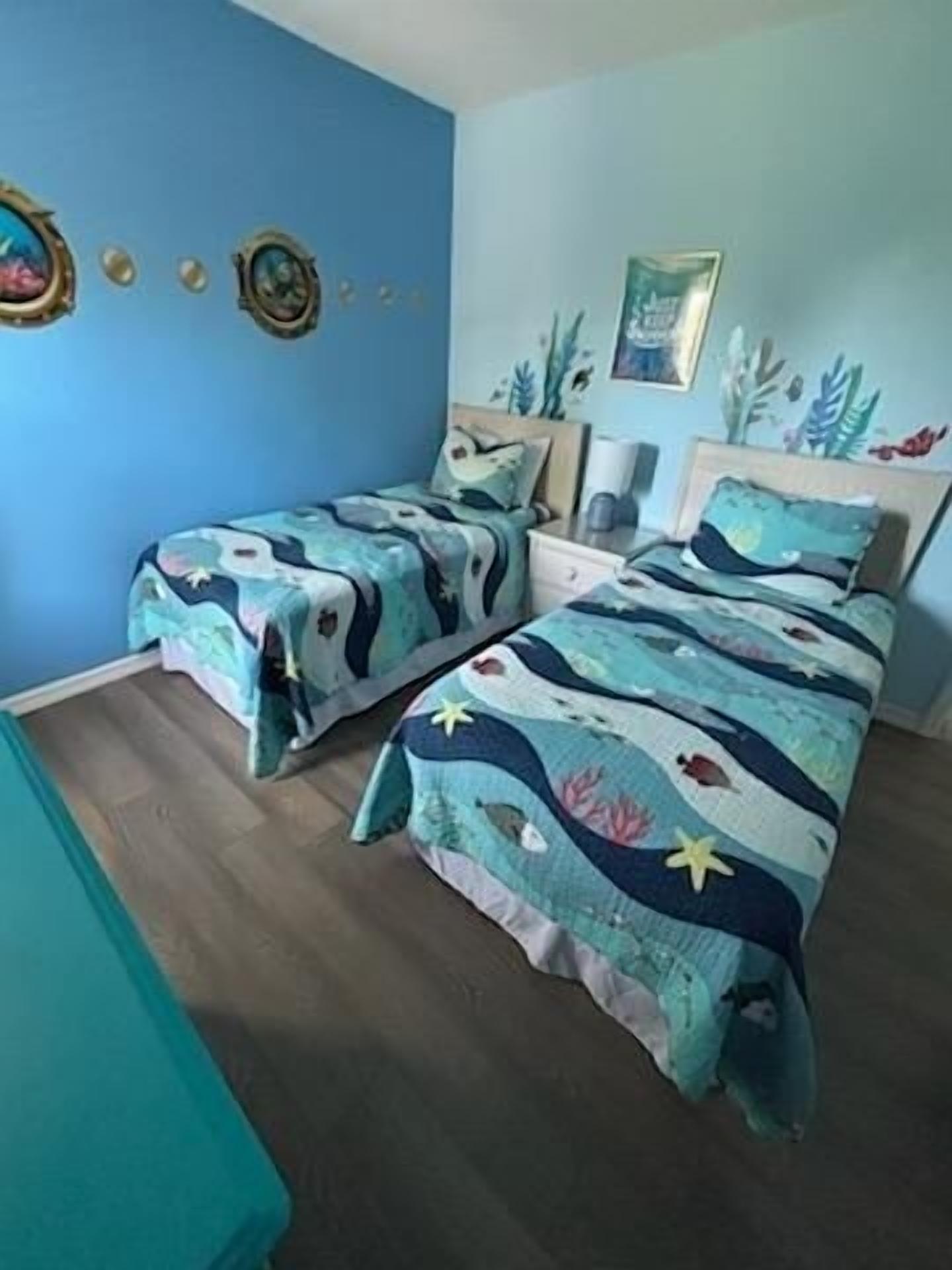 A bedroom with two beds, a nightstand, and a wall decorated with marine-themed artwork.