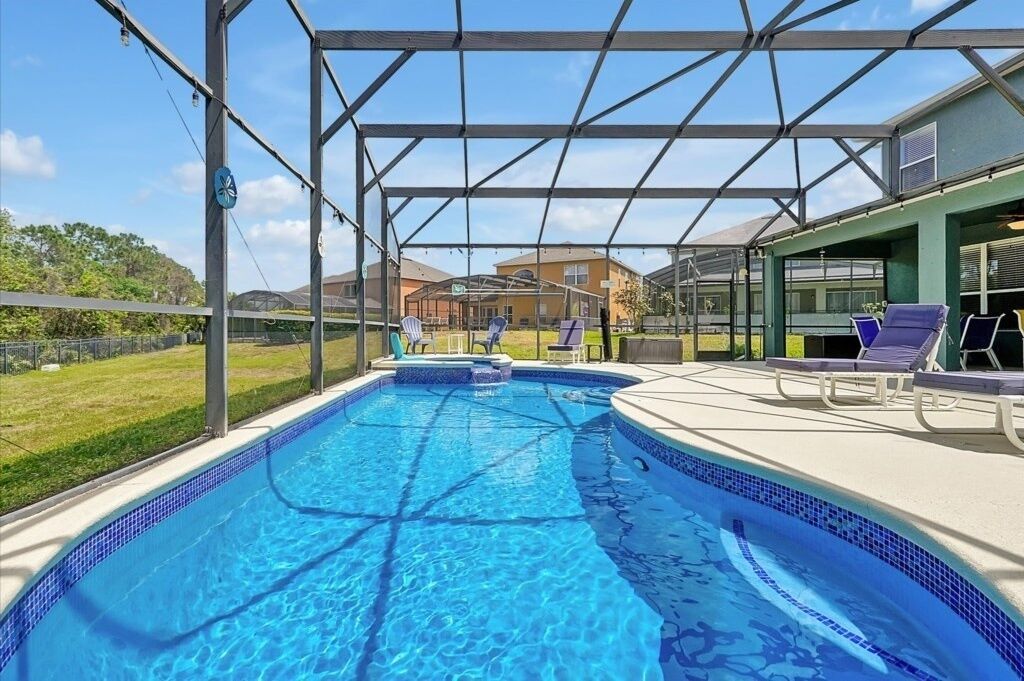 A swimming pool with a covered area, lounge chairs, and a view of surrounding buildings.