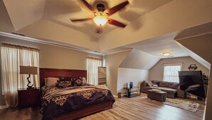 Un ampli dormitori amb un llit gran, un ventilador de sostre i vista a la zona d'estar.