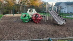 Un parc infantil amb tobogan, cadira de balanceig i elements per a escalar.