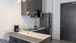 Una cocina moderna con una isla central, taburetes de bar, microondas integrado y un refrigerador.
