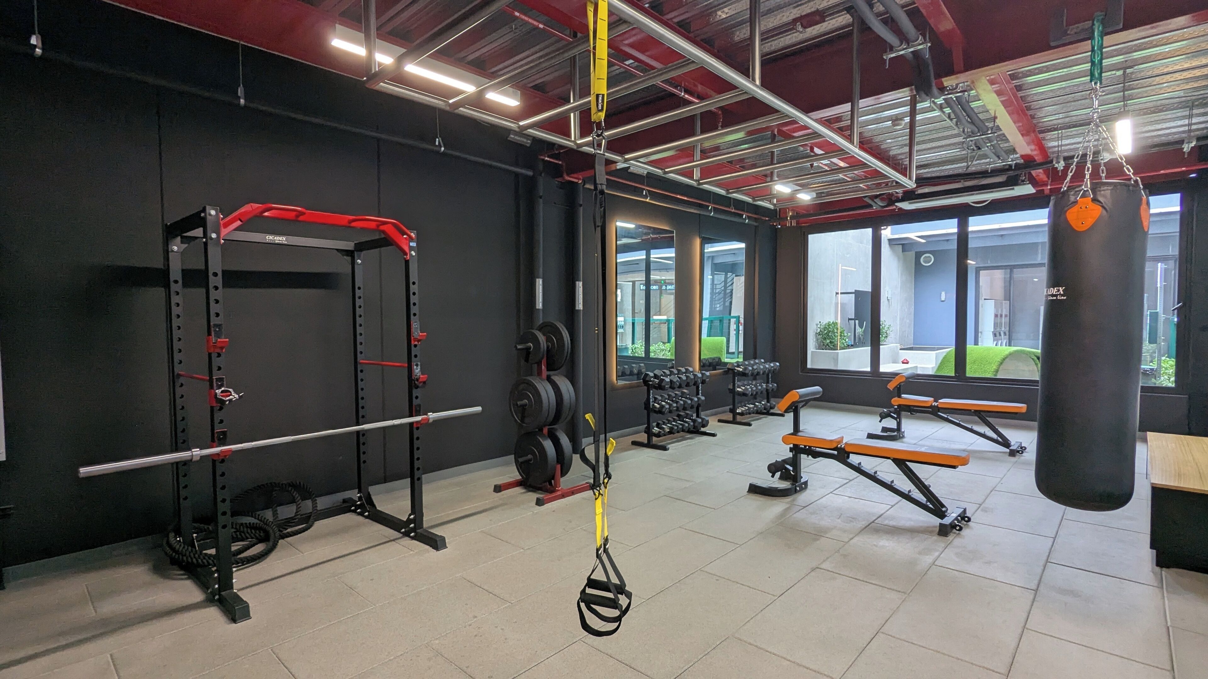 Una palestra con attrezzatura per sollevamento pesi, panche e un sacco da boxe.