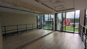 Una habitación amplia con suelo de madera, ventanas grandes y una lámpara de techo moderna.
