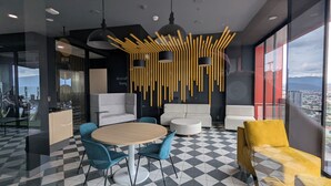 Un interior moderno con una mesa redonda, sillas azules, sofás blancos y un sillón amarillo.