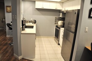 A modern kitchen with white cabinets, a stainless steel refrigerator, and a tiled backsplash.