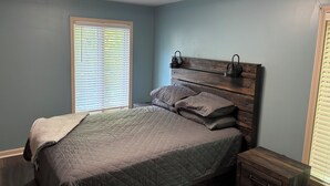 A bedroom with a bed, a nightstand, and a wall-mounted light fixture.