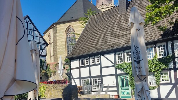 An outdoor seating area with tables and chairs, a Coca-Cola barrel, and umbrellas. - Small romantic house in the "Burgviertel" (old town) (Unna)
