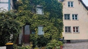 A house covered in ivy with a traditional design, a front door, and a small porch area with potted plants. - Small romantic house in the "Burgviertel" (old town) (Unna)